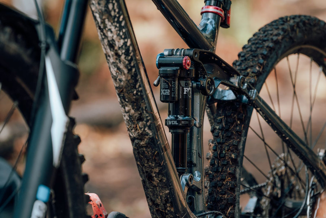 Close-up of a mud-spattered mountain bike frame and suspension fork after a trail ride