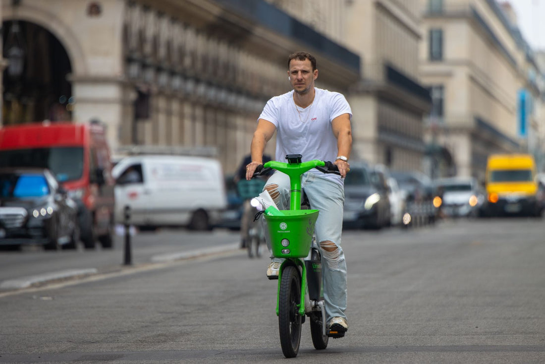 Man riding a green electric bike along a busy city street