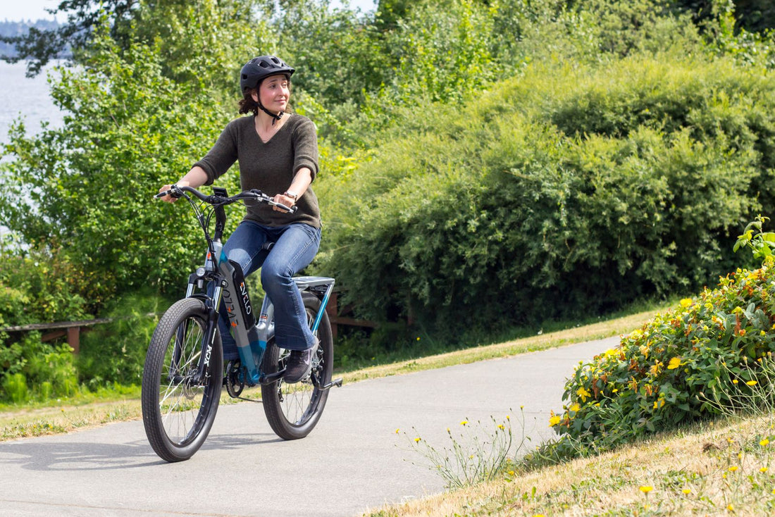 Woman riding a step-through electric bike along a paved city path