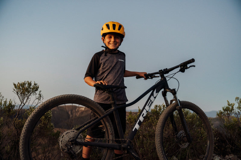Kid standing with a Trek mountain bike
